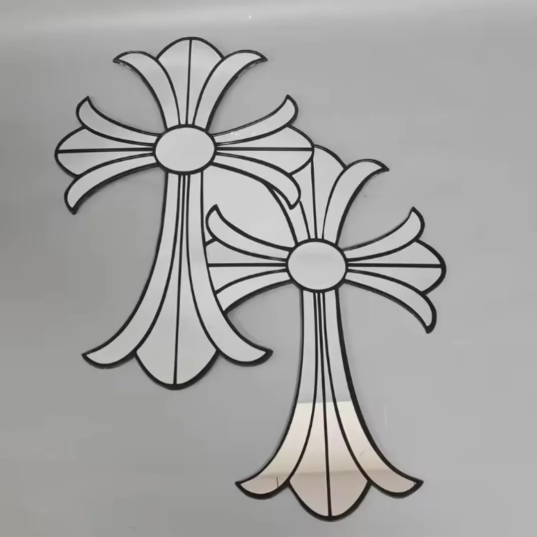 Two stylized gothic cross-shaped mirrors with thick black outlines lying flat against a light grey background.