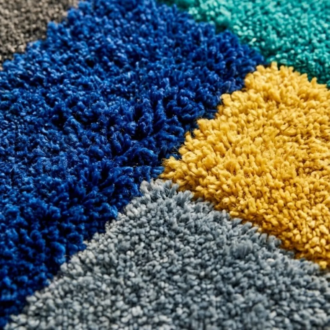 harbor mosaic rug texture Close-up texture detail of the Harbor Mosaic rug, highlighting the dense, plush hand-tufted wool piles in vibrant blue, mustard yellow, and soft grey.