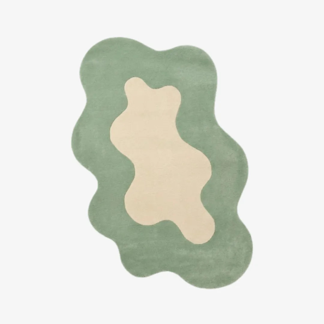 Top-down view of the Liom Mist rug featuring a fluid, organic wavy silhouette and a soft sage green border surrounding a central cream-colored abstract shape.