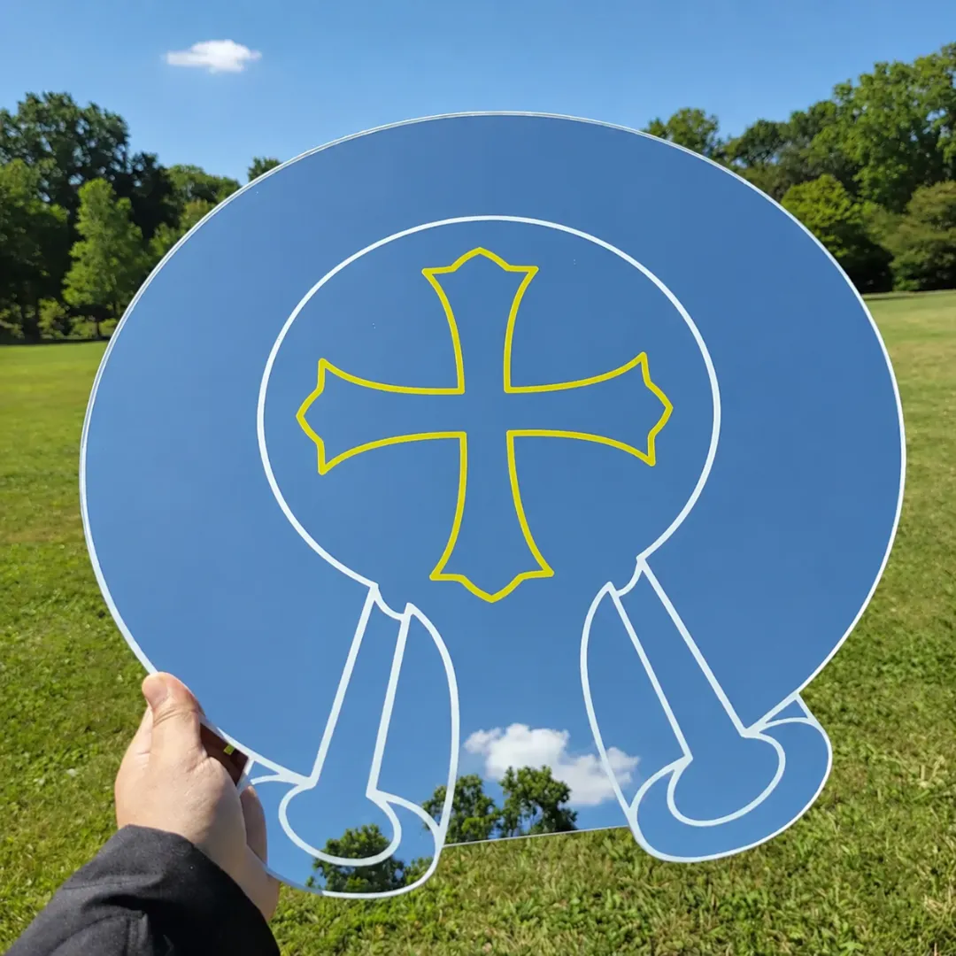 Round modern gothic cross mirror with multicolor typography placed on grass flat lay outdoor decor