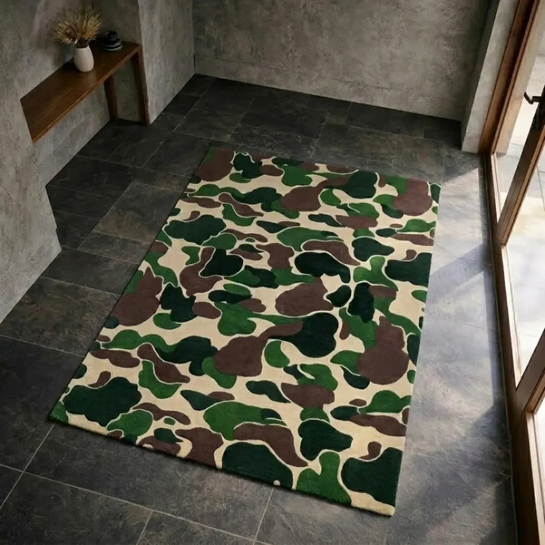 shadowfield camo terrain area rug product shot A top-down studio product photograph of a rectangular area rug featuring a tactical camouflage pattern in green, brown, and cream, displayed on dark tiled flooring.