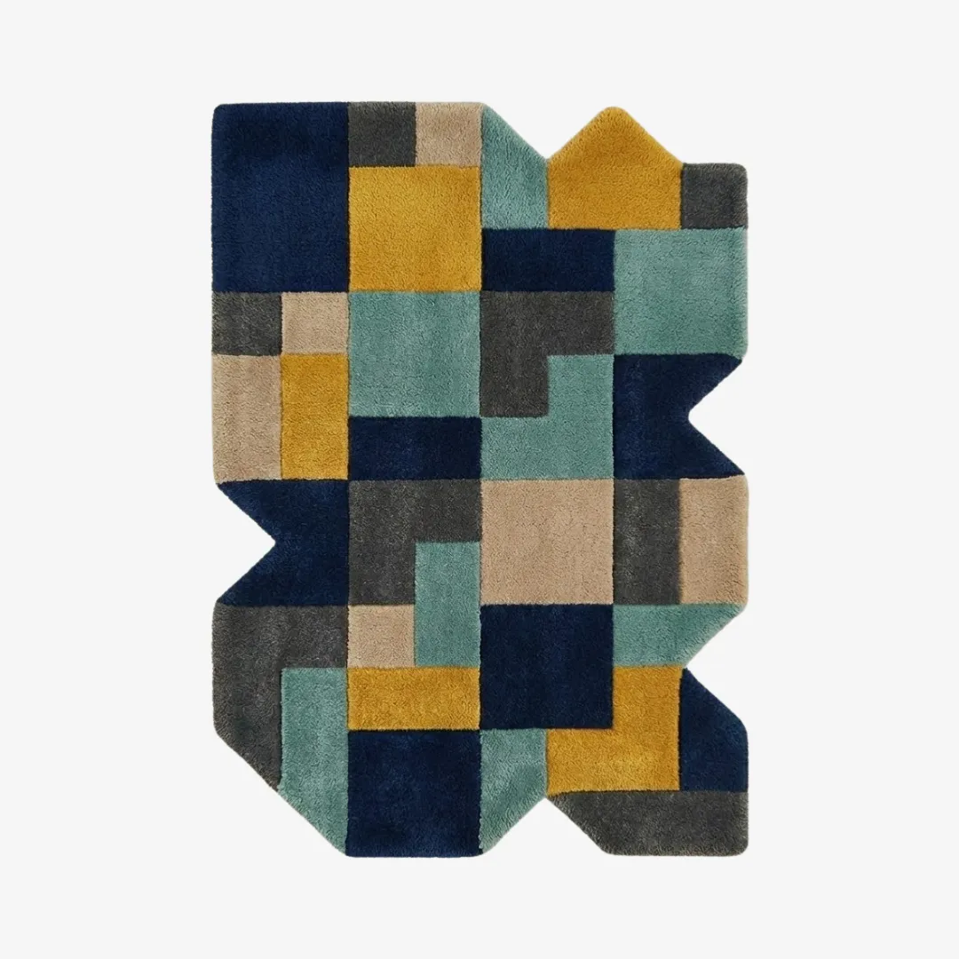 Top-down view of the Urban Relic rug featuring a complex, jagged irregular silhouette and a dense geometric patchwork of navy blue, teal, mustard yellow, and charcoal grey blocks.