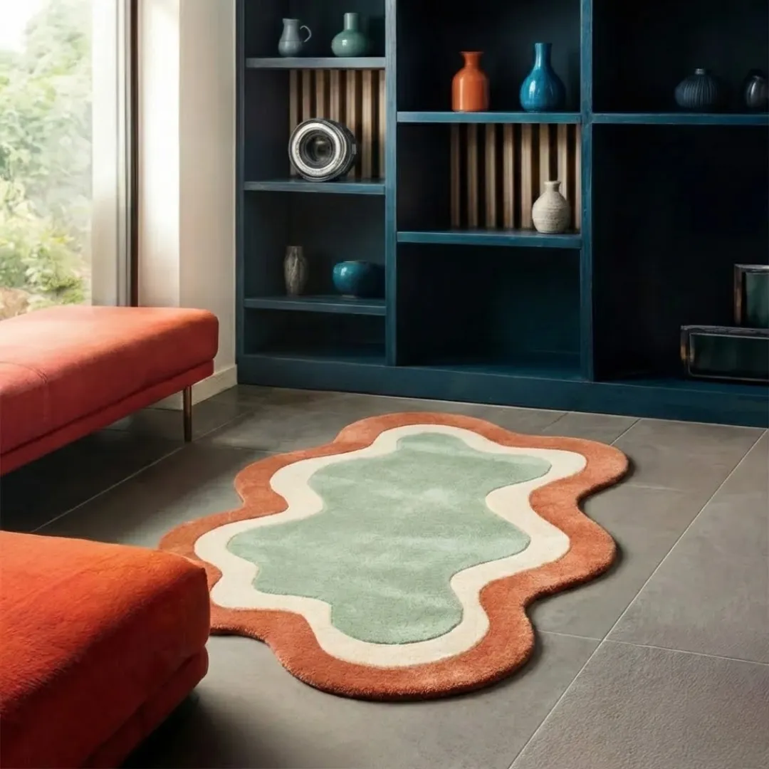 Perspective lifestyle view of the Wellonest rug on a grey tile floor, styled with orange velvet benches to highlight its unique wavy border and warm earth-toned palette.