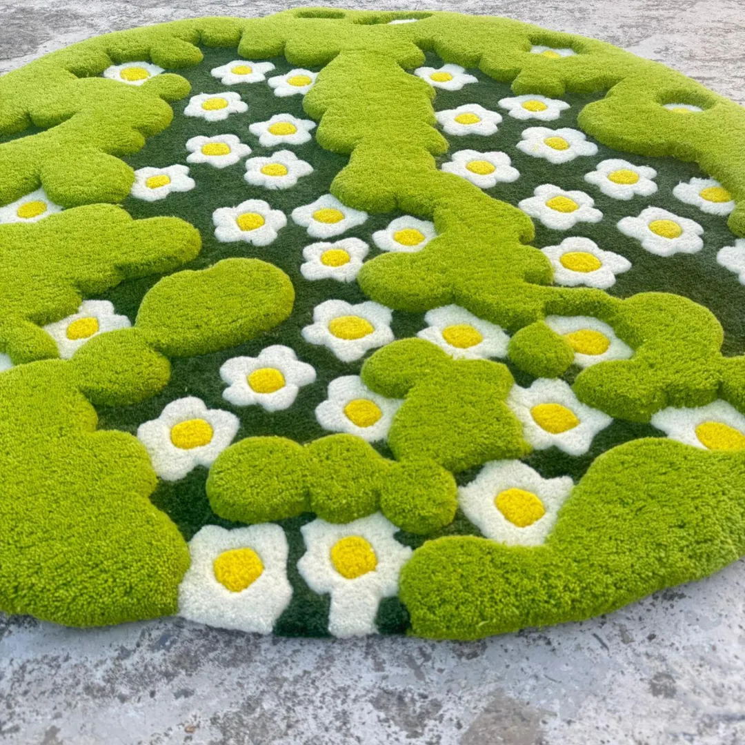 Angled shot of the round 3-D Moss Rug displayed on a concrete floor. The lower perspective emphasizes the three-dimensional, multi-level tufting, showing how the bright green cloud-like moss shapes pop out from the floral daisy background.