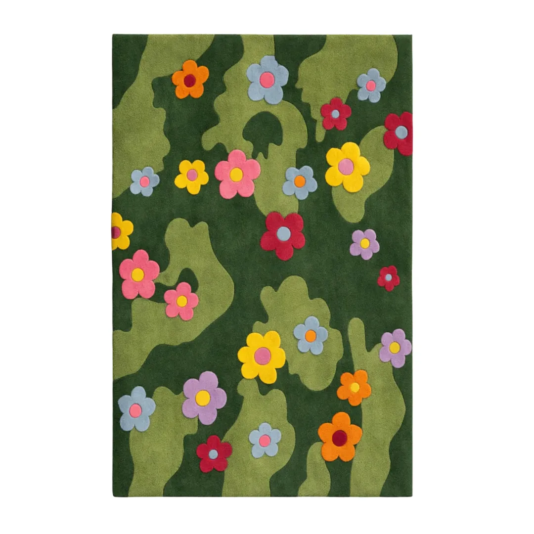 A flat, overhead shot of the Daisy Meadow Rug. The design showcases a hand-tufted abstract pattern of light and dark green waves, decorated with colorful pink, yellow, blue, red, orange, and purple daisies.