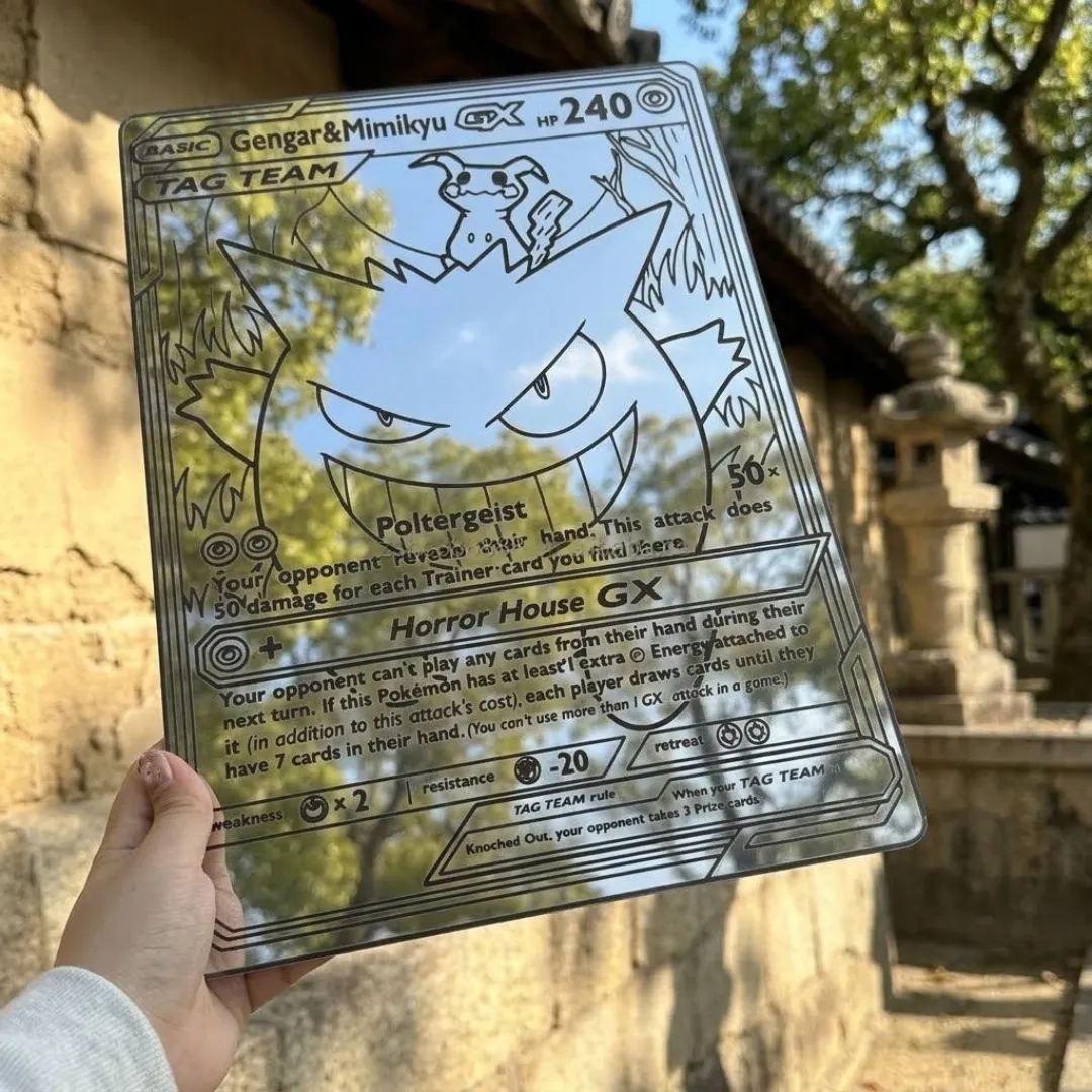ghost duo mirror decor hand Hand holding the Ghost Duo Mirror Wall Decor outdoors, displaying its engraved trading card aesthetic while reflecting a bright sky and nearby trees.