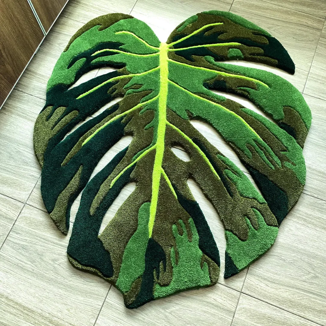 Full overhead view of the Monstera Flux Rug laying completely flat on a light tiled floor, showcasing its intricate cut-out edges and rich green tufted shading.