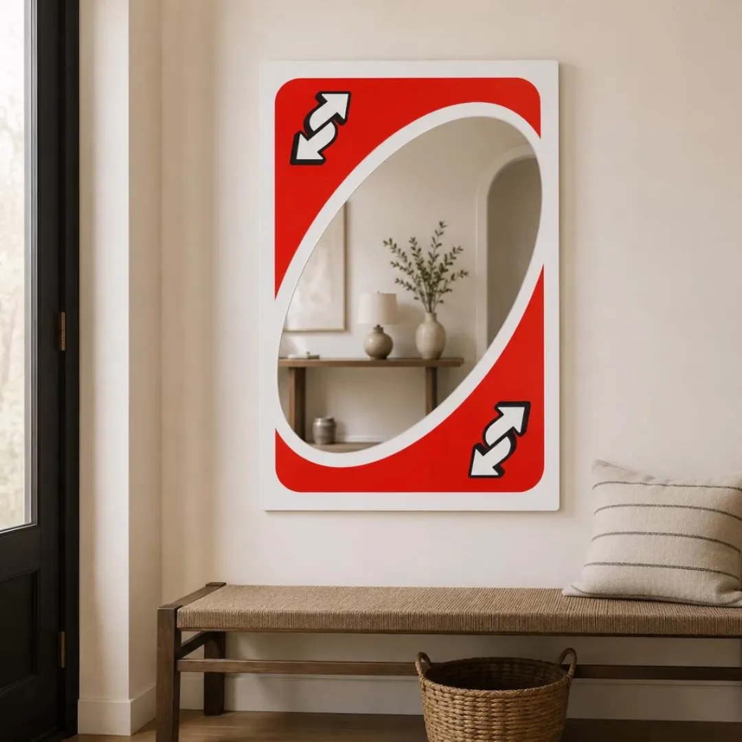 flip frame reverse card mirror living room decor Front-facing shot of the Flip Frame mirror, designed to resemble a classic red reverse card, mounted on a cream-colored wall above a wooden bench.