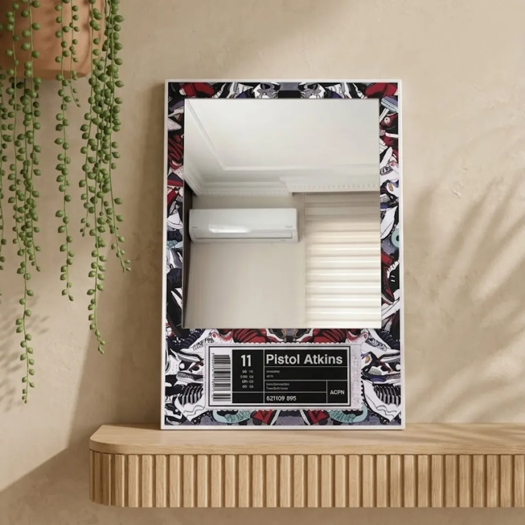 A close-up view of the "Pistol Atkins" sneaker graphic mirror resting on a ribbed light wood console shelf, showcasing the intricate shoe pattern and reflective surface.