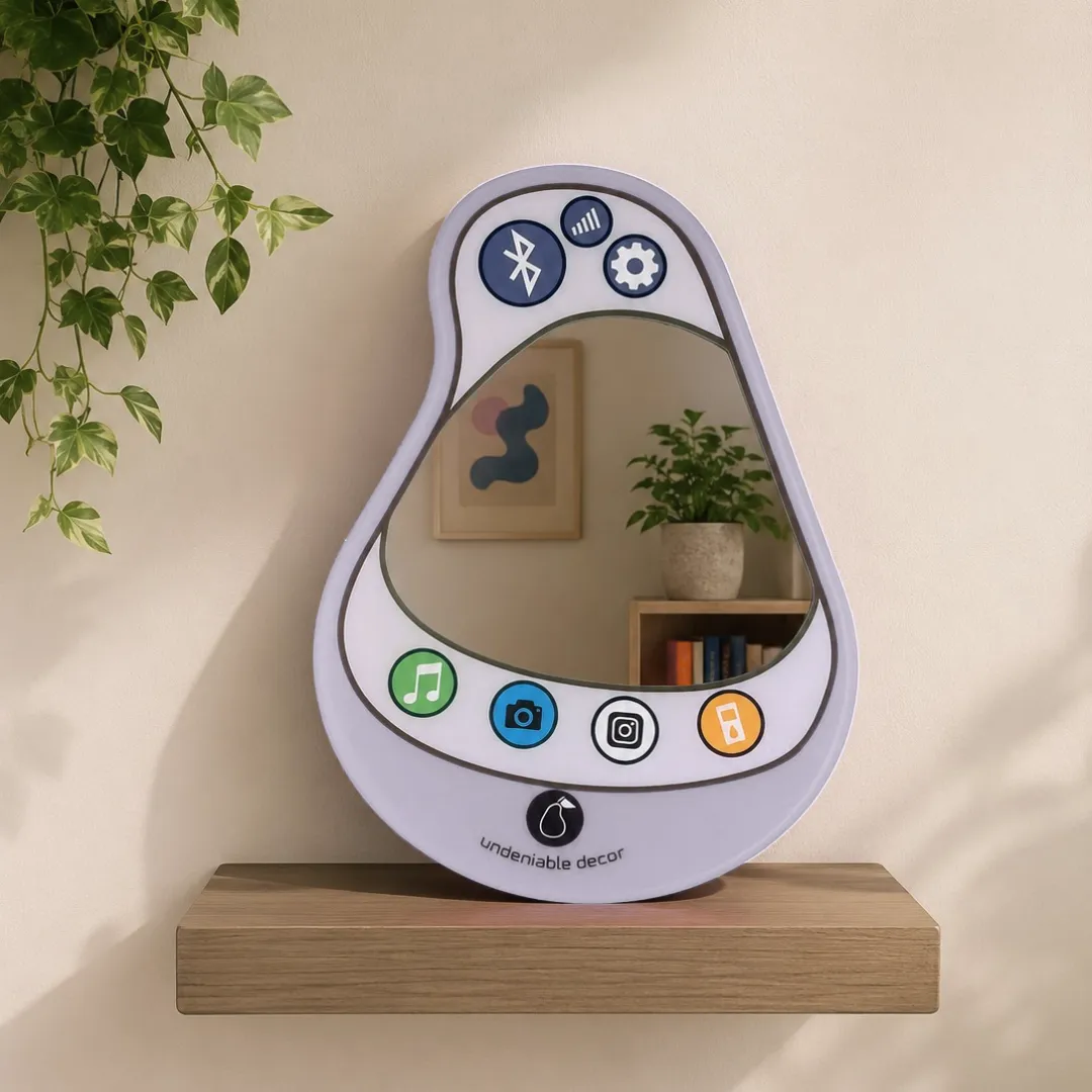 pear connect grey phone mirror lifestyle shelf decor Lifestyle view of the light grey Pear Connect phone mirror styled on a floating wooden shelf against a neutral wall, accompanied by a trailing green plant.