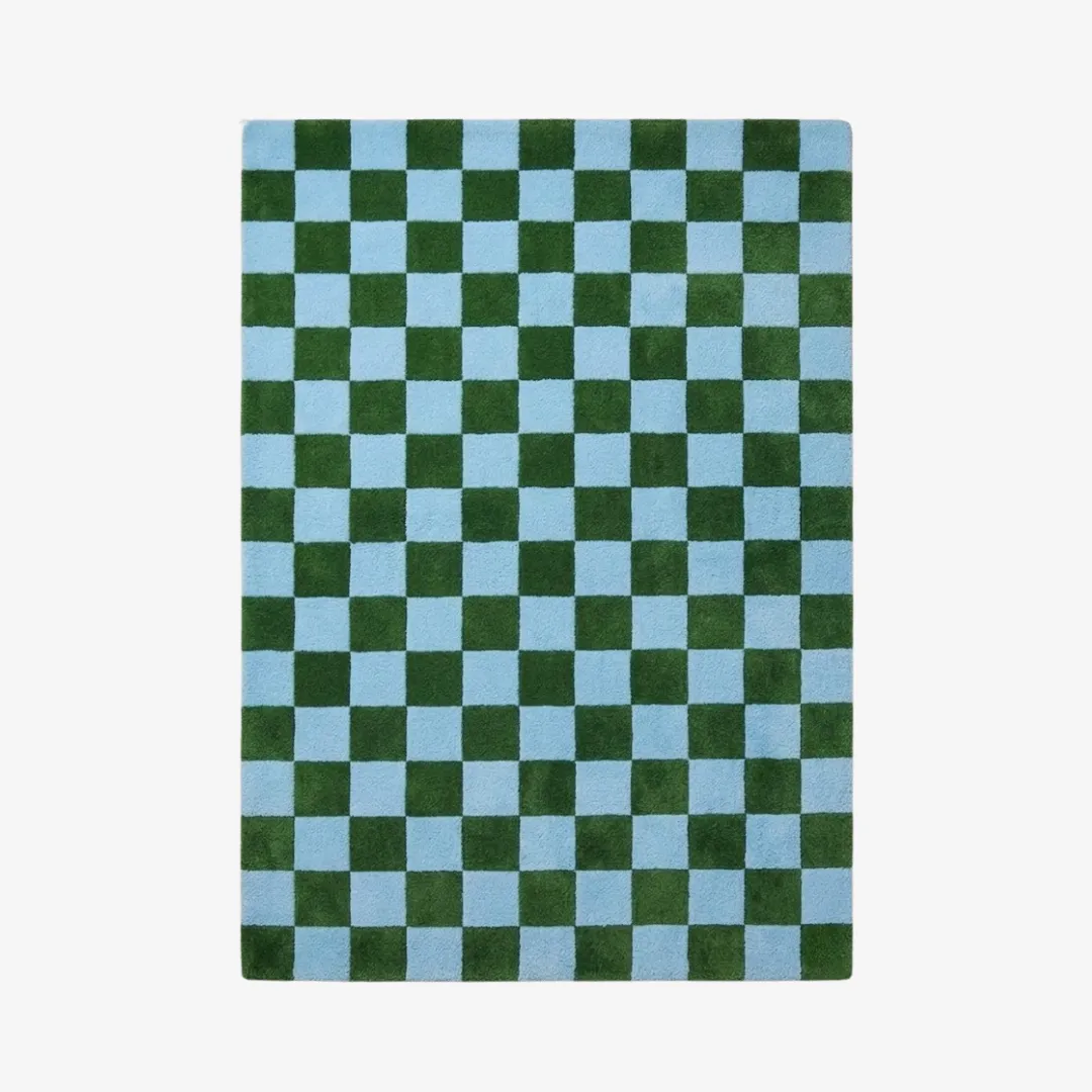 A top-down studio product photograph of the rectangular Sage Check area rug, featuring a vibrant, repeating checkerboard pattern in contrasting forest green and sky blue.