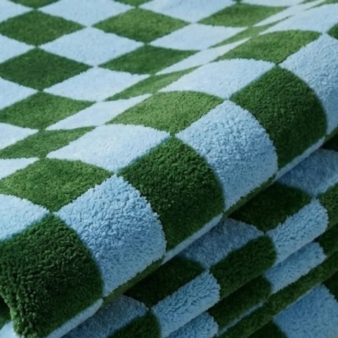 A macro close-up of the folded Sage Check rug, focusing on the dense, tufted wool pile and the crisp, alternating green and blue checkerboard construction.