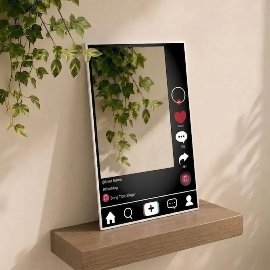 Angled view of the Social Frame mirror, mimicking a social media post interface, positioned on a wooden shelf against a beige wall with hanging ivy foliage.