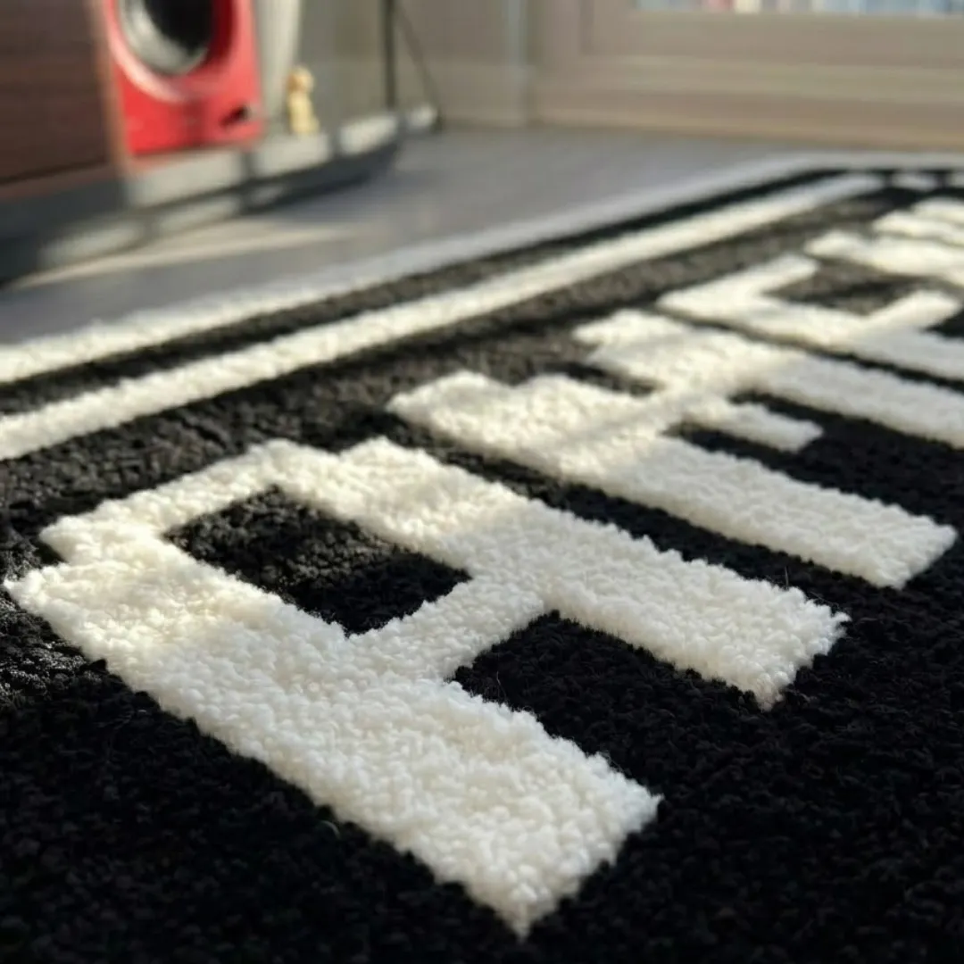 amen rug close up texture view Close-up macro texture shot of the high-density tufted wool pile and clean carved letter outlines on the Amen designer rug.