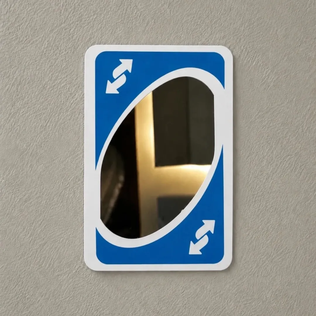 Blue Card Shift reverse game card wall mirror mounted in a warm interior setting next to framed art and a table lamp.