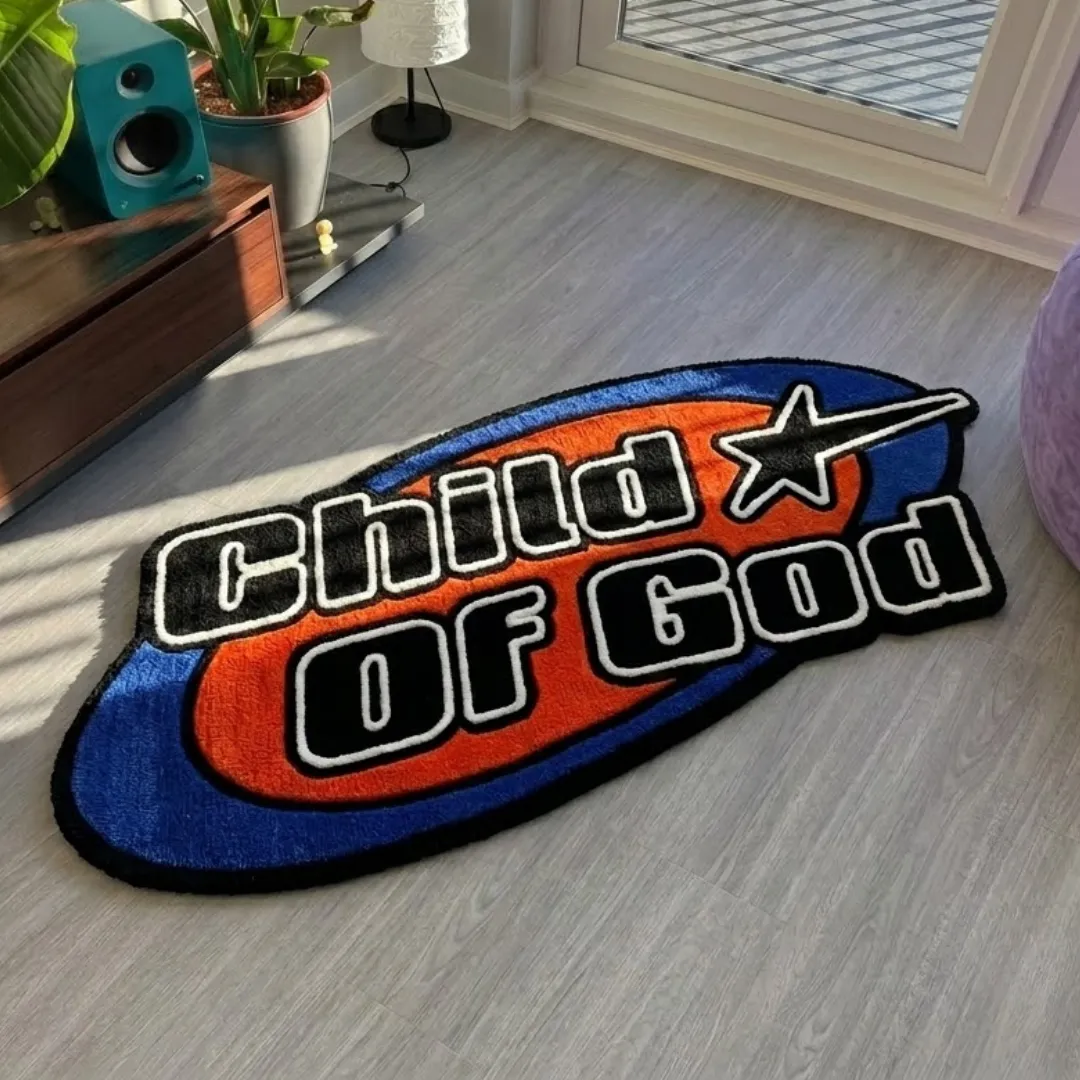 child of good rug top view Child Of Good handmade tufted area rug featuring a vibrant blue, orange, and black design with star and typography elements, displayed flat on a light wood floor.