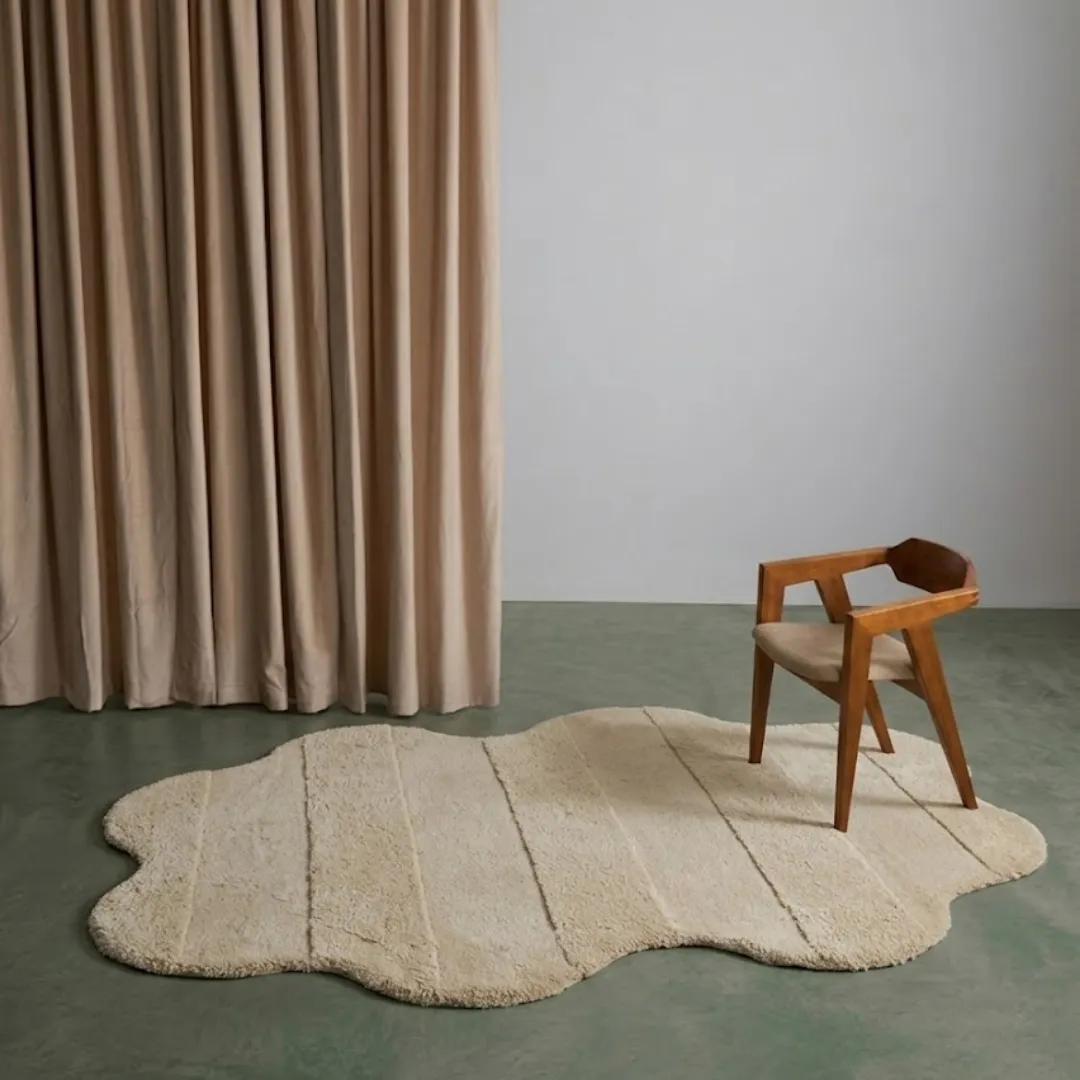 Cloud Ripple neutral organic tufted area rug styled in a modern minimalist interior room with a wooden chair and beige curtains.