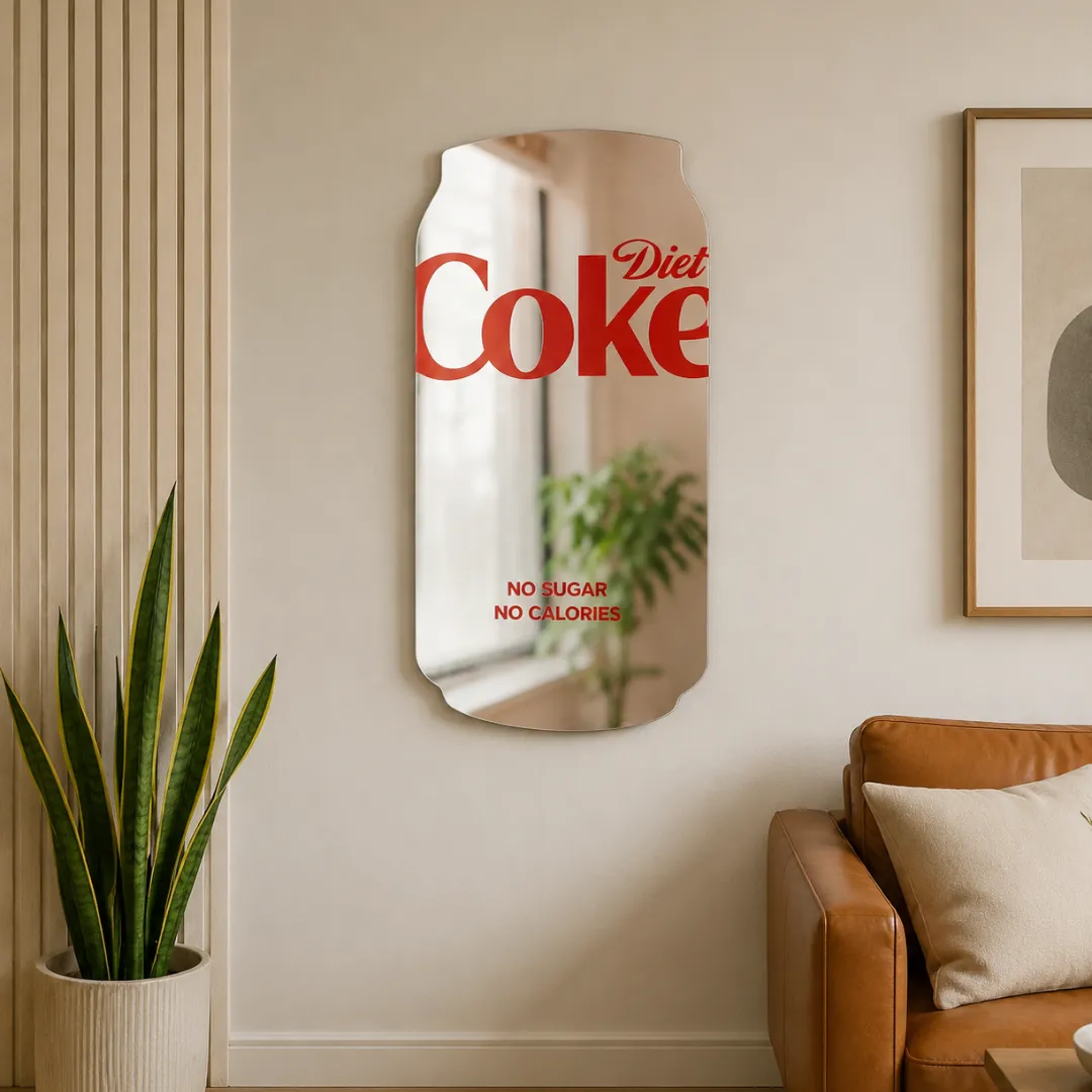 Cola Pop Mirror novelty soda can wall mirror styled in a modern living space above a tan leather sofa next to potted plants.