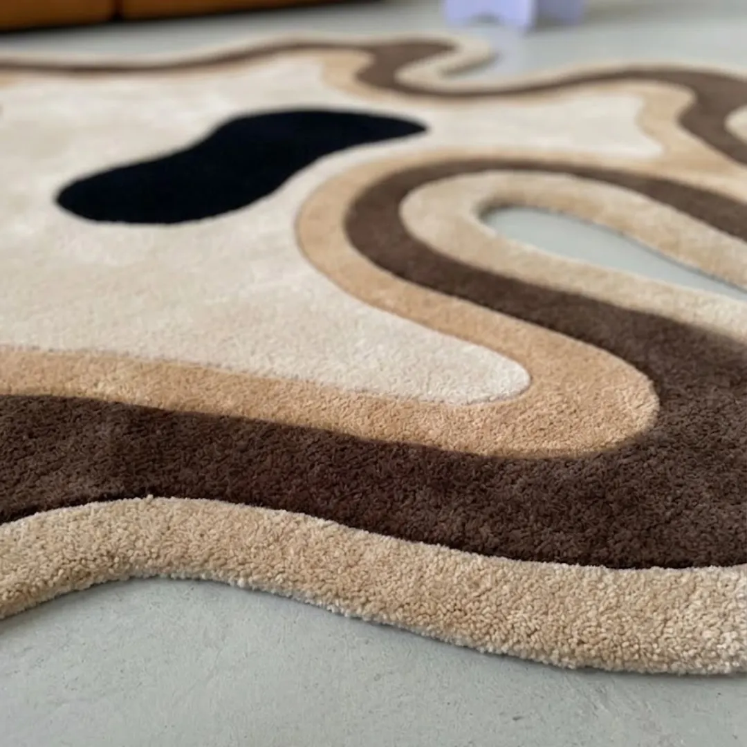 Close-up of the plush tufted pile texture, flowing topographic layers, and rich brown, tan, and cream color palette on the Desert Flow rug.