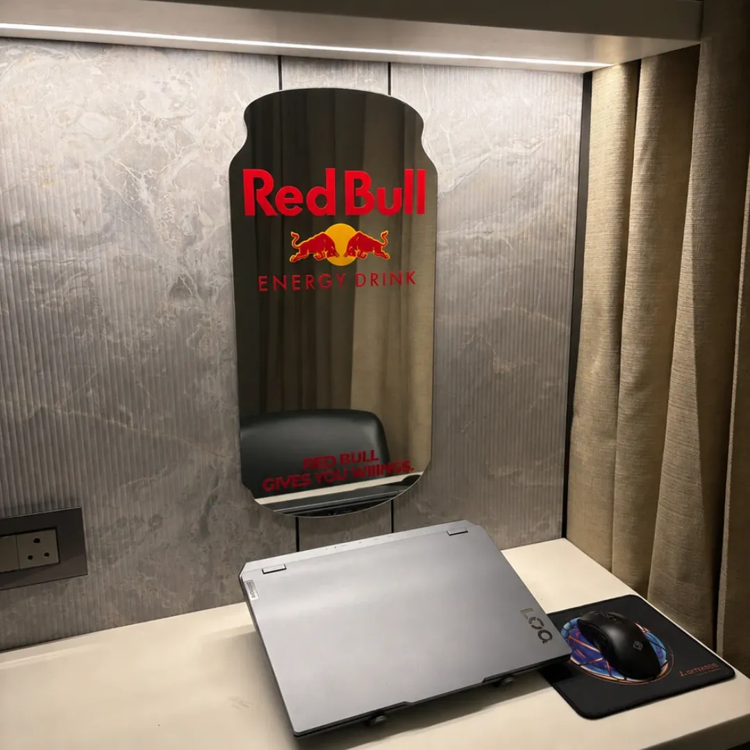lunavex mirror desk setup view Lunavex decorative wall mirror featuring a custom Red Bull energy drink can design, mounted on a textured marble wall above a desk with a laptop.
