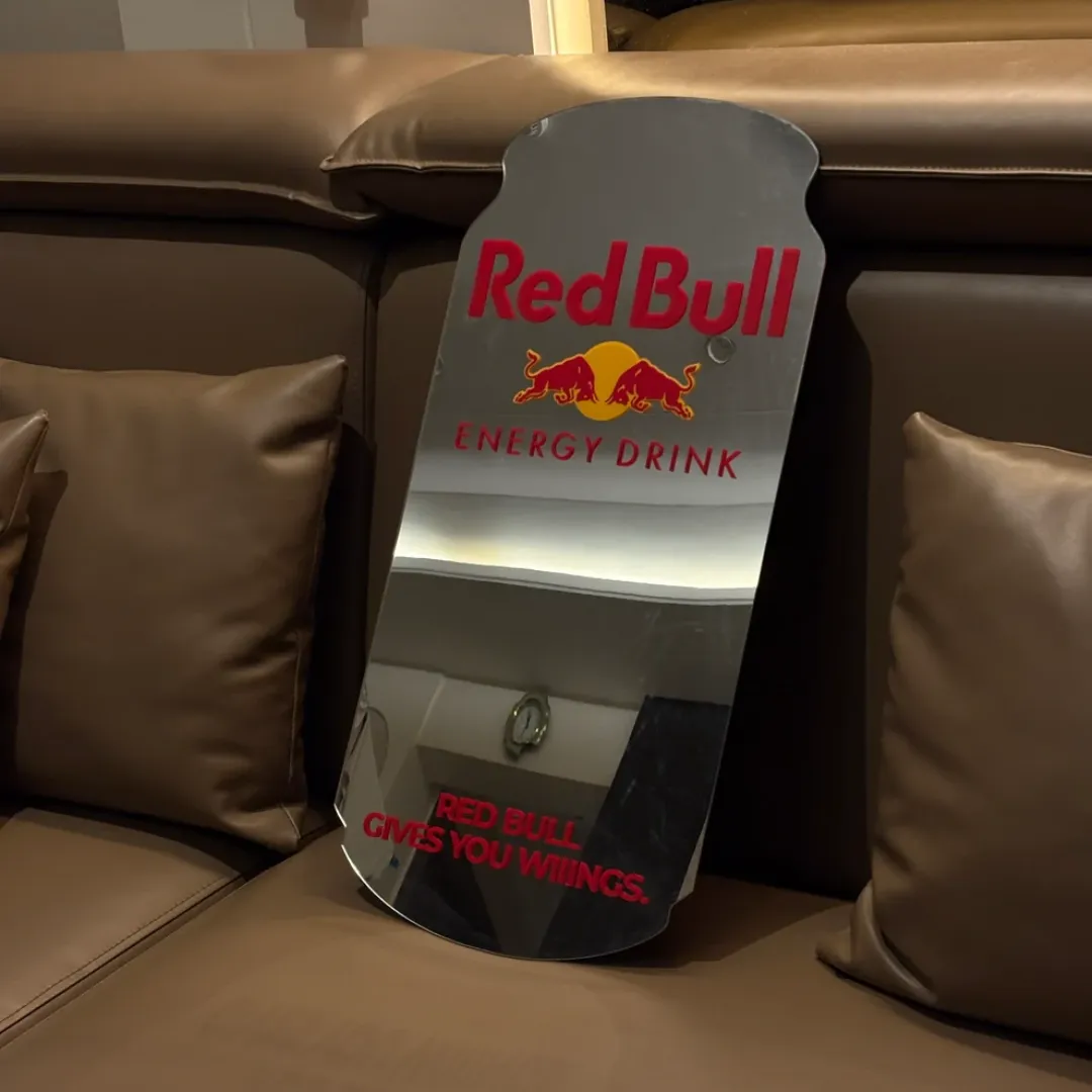 lunavex mirror sofa display view Lunavex novelty energy drink can wall mirror placed on a brown leather sofa cushion showcasing its unique silhouette and branding graphics.