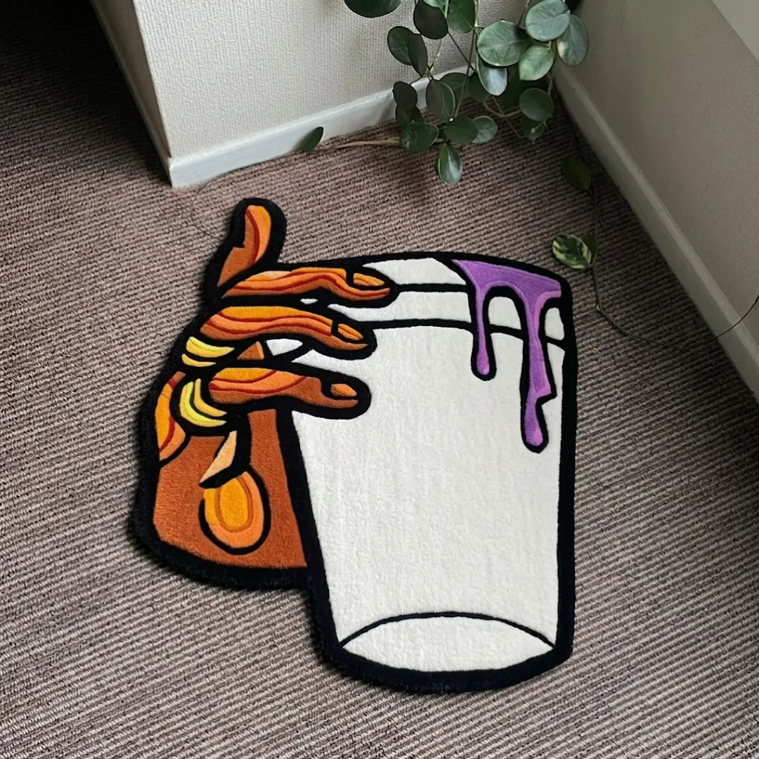 melting cup rug top view Melting Cup handmade tufted area rug featuring a graphic hand holding a cup with a purple liquid spill, displayed flat on a carpeted floor.