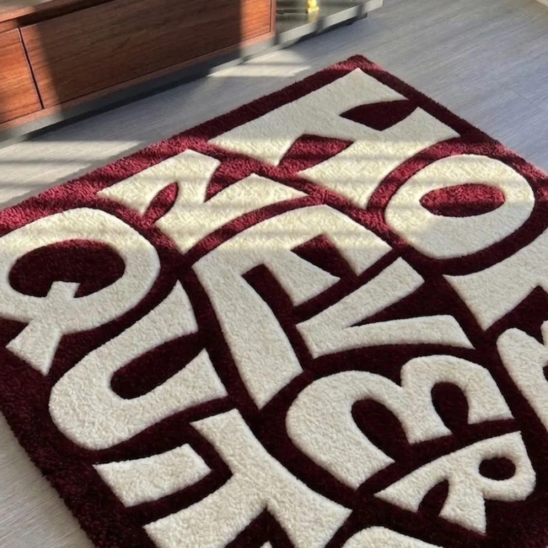 Close-up texture shot of the high-density tufted wool pile and clean typography details on the Never Quits designer rug.