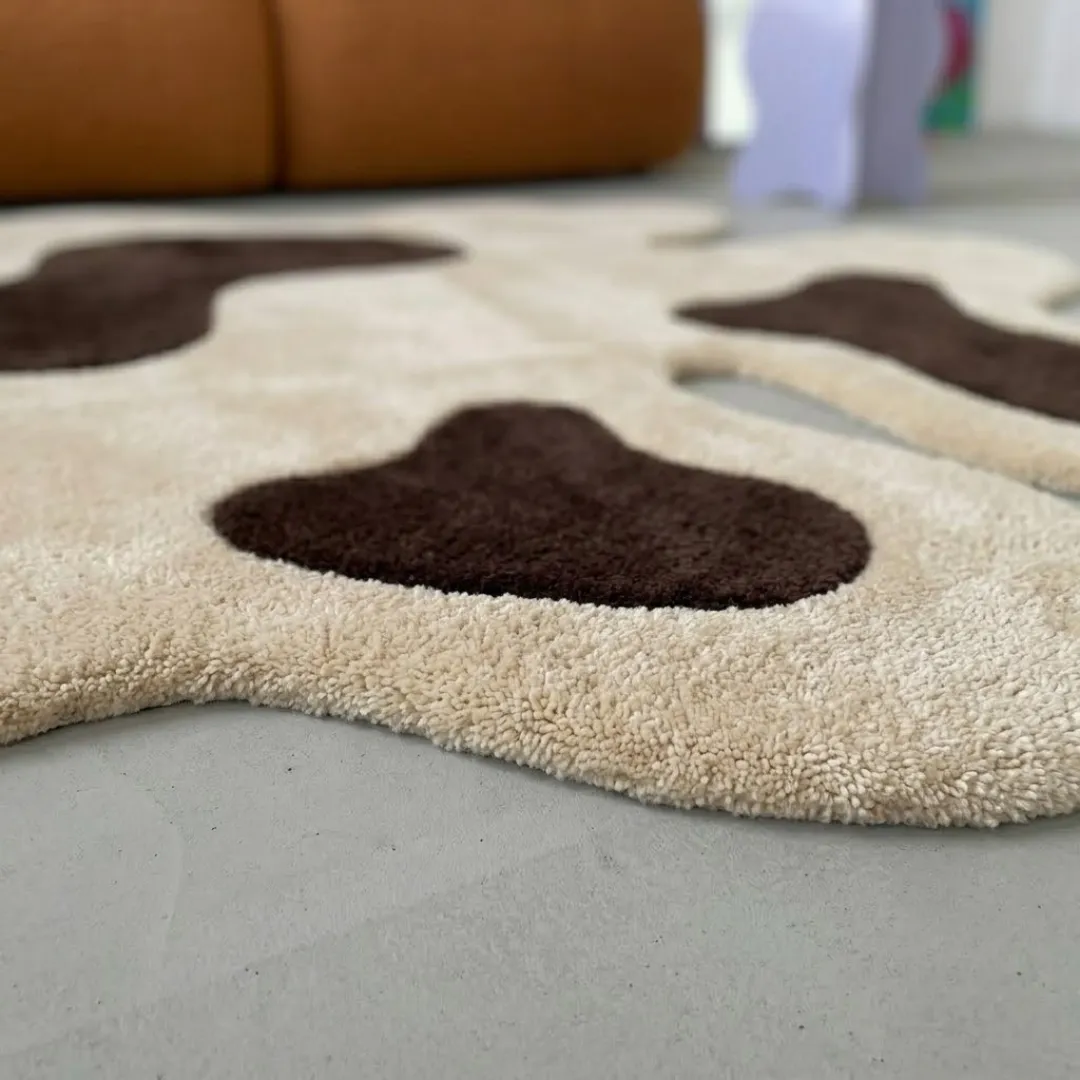 oat muse rug close up texture Close-up of the plush tufted pile texture, soft cream background, and rich dark brown spot details on the Oat Muse rug.