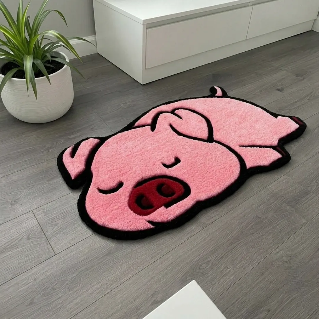 poppy snore rug angle view Angle view of the Poppy Snore tufted novelty rug showcasing its unique pig silhouette, plush pink wool pile, and black outlining on a gray wood floor.