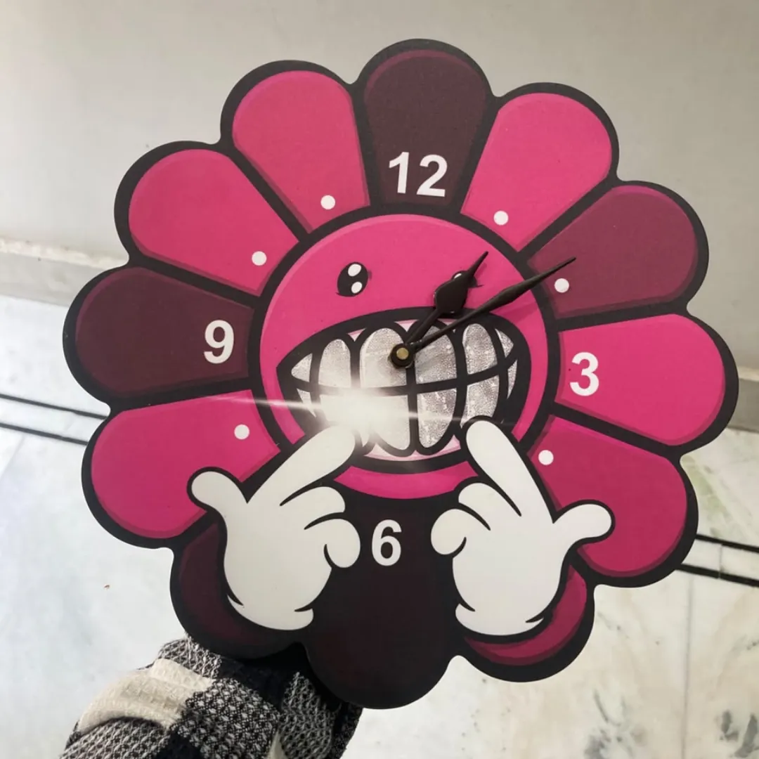 smiley bloom clock hand held view Smiley Bloom colorful flower clock featuring a cartoon character face and grillz design, held by hand.