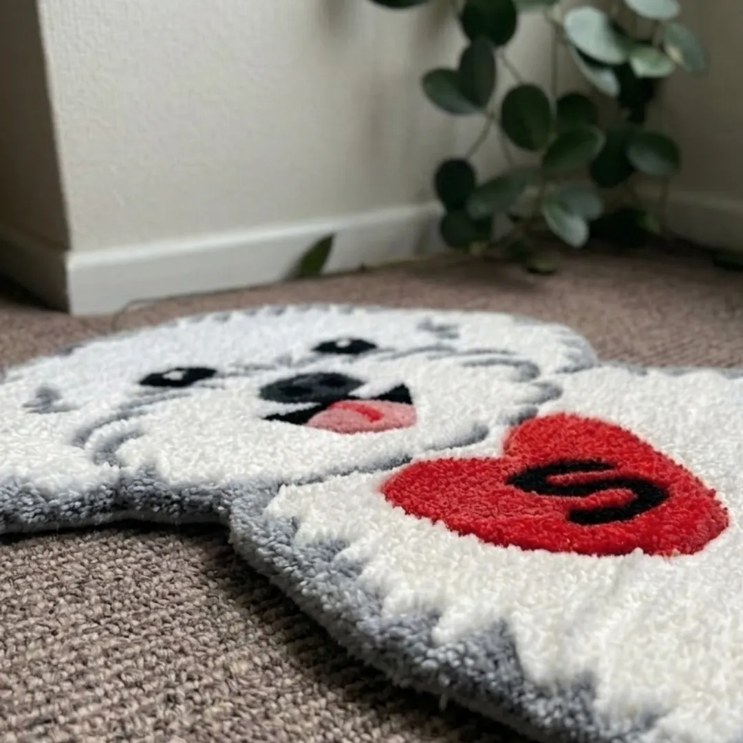 Close-up macro texture shot of the high-density tufted wool pile, carved contours, and textured red heart motif on the Snowy Heart designer rug.