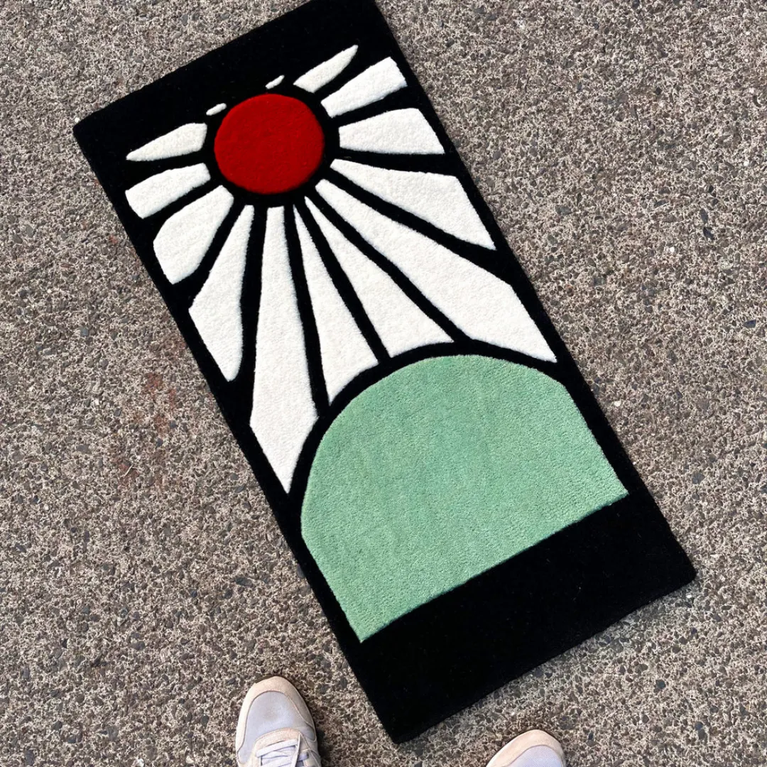 Angle view of the Sunrise Horizon designer rug laid out outdoors, highlighting its rectangular shape and detailed graphic motif.