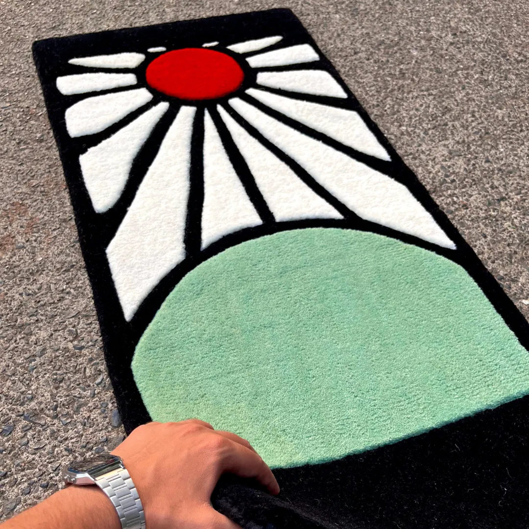 Hand-held angle view of the Sunrise Horizon tufted rug showcasing its plush pile texture, clean black outlines, and vibrant color blocking.
