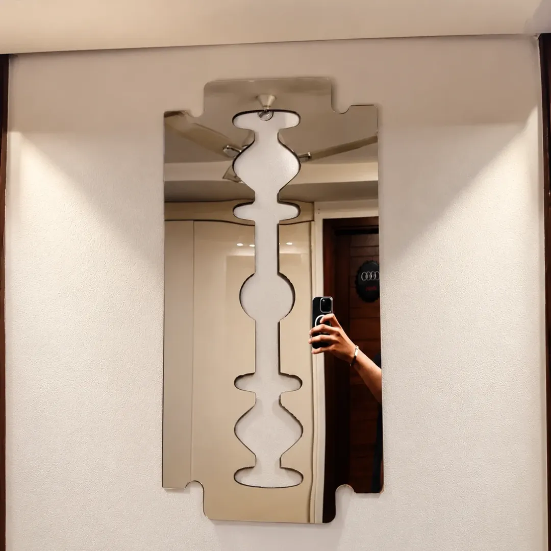 Symmetry geometric wall mirror reflecting a person taking a mirror selfie in a modern interior setting.