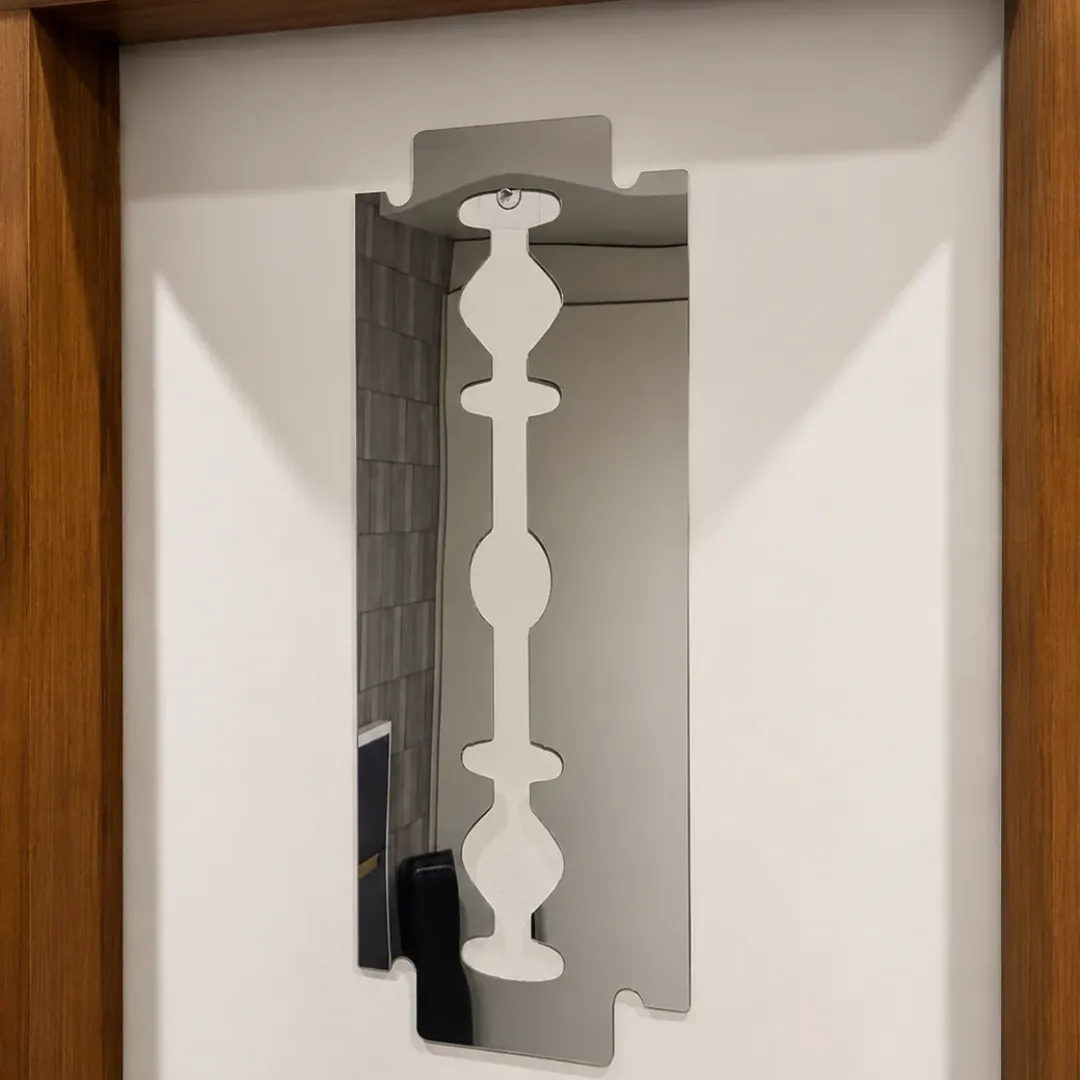 Symmetry decorative wall mirror styled in a modern entryway above a console table with a vase of greens and books.