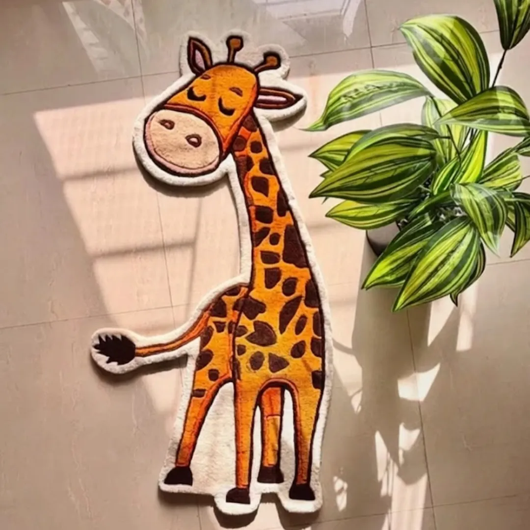 Tallie Jive handmade tufted area rug featuring a playful cartoon giraffe shape with orange and brown spots, displayed flat on a tiled floor next to a potted plant.