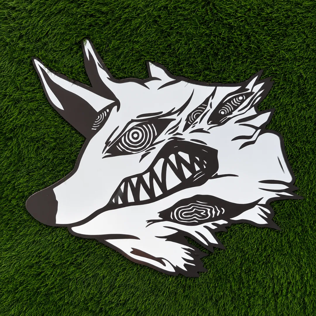 Vevron Wolf decorative wall mirror featuring a surreal wolf head design with hypnotic eye patterns and sharp teeth, placed outdoors on a green grass background.