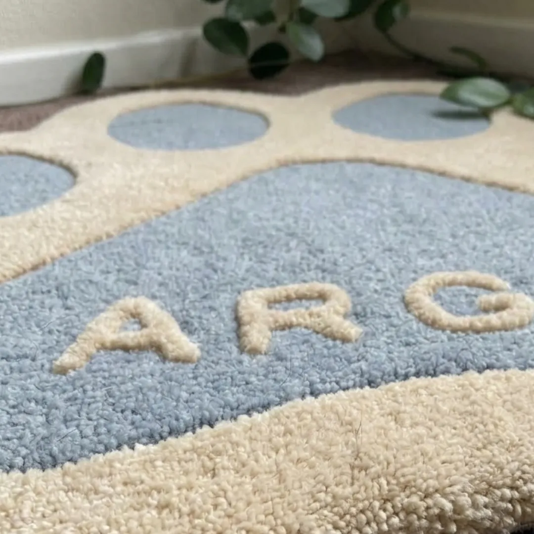 cloud paw rug low angle view Close-up macro texture shot of the high-density tufted wool pile, carved contours, and textured lettering on the Cloud Paw designer rug.