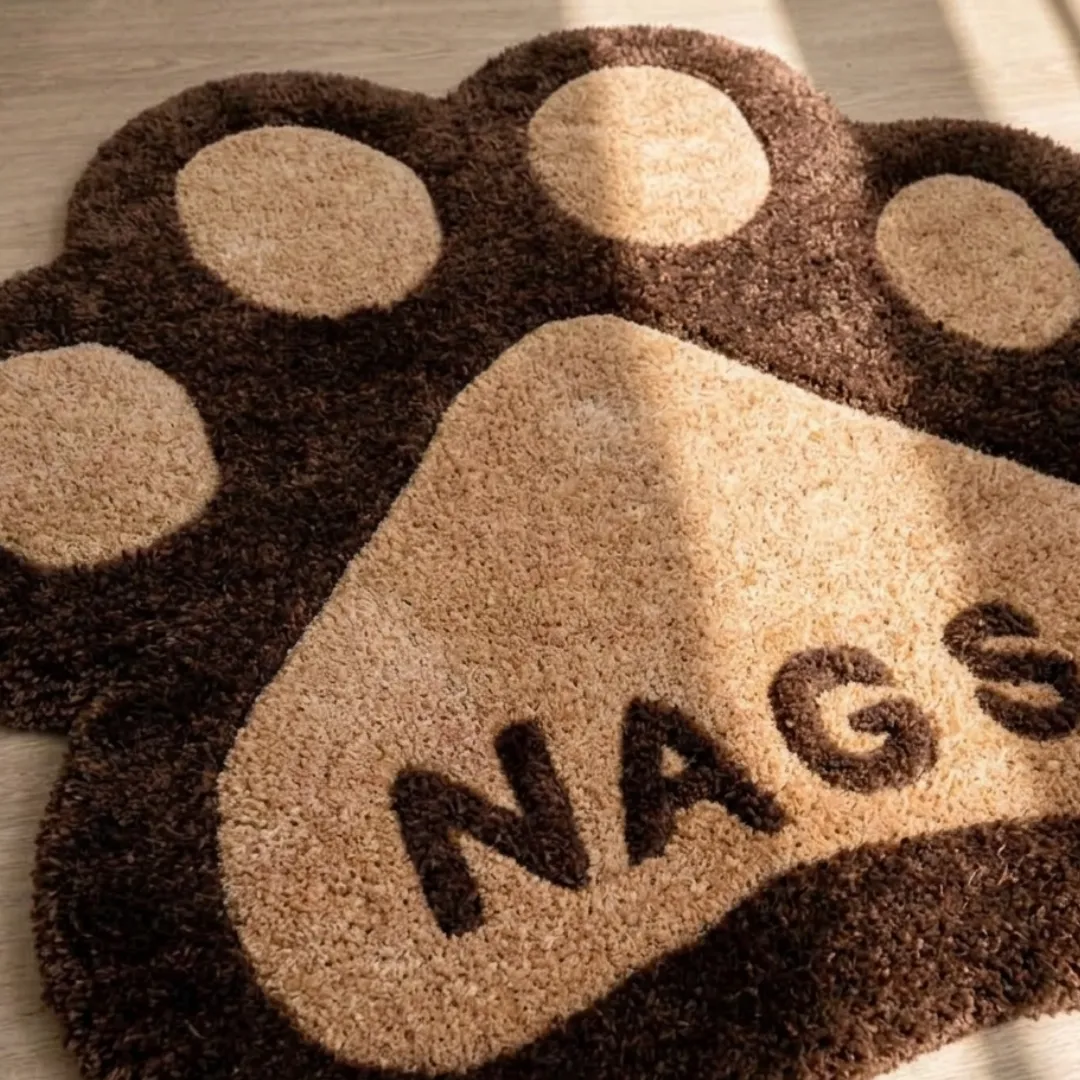 cocoa paw rug close up texture view Close-up macro texture shot of the high-density tufted wool pile, carved contours, and textured lettering on the Cocoa Paw novelty rug.