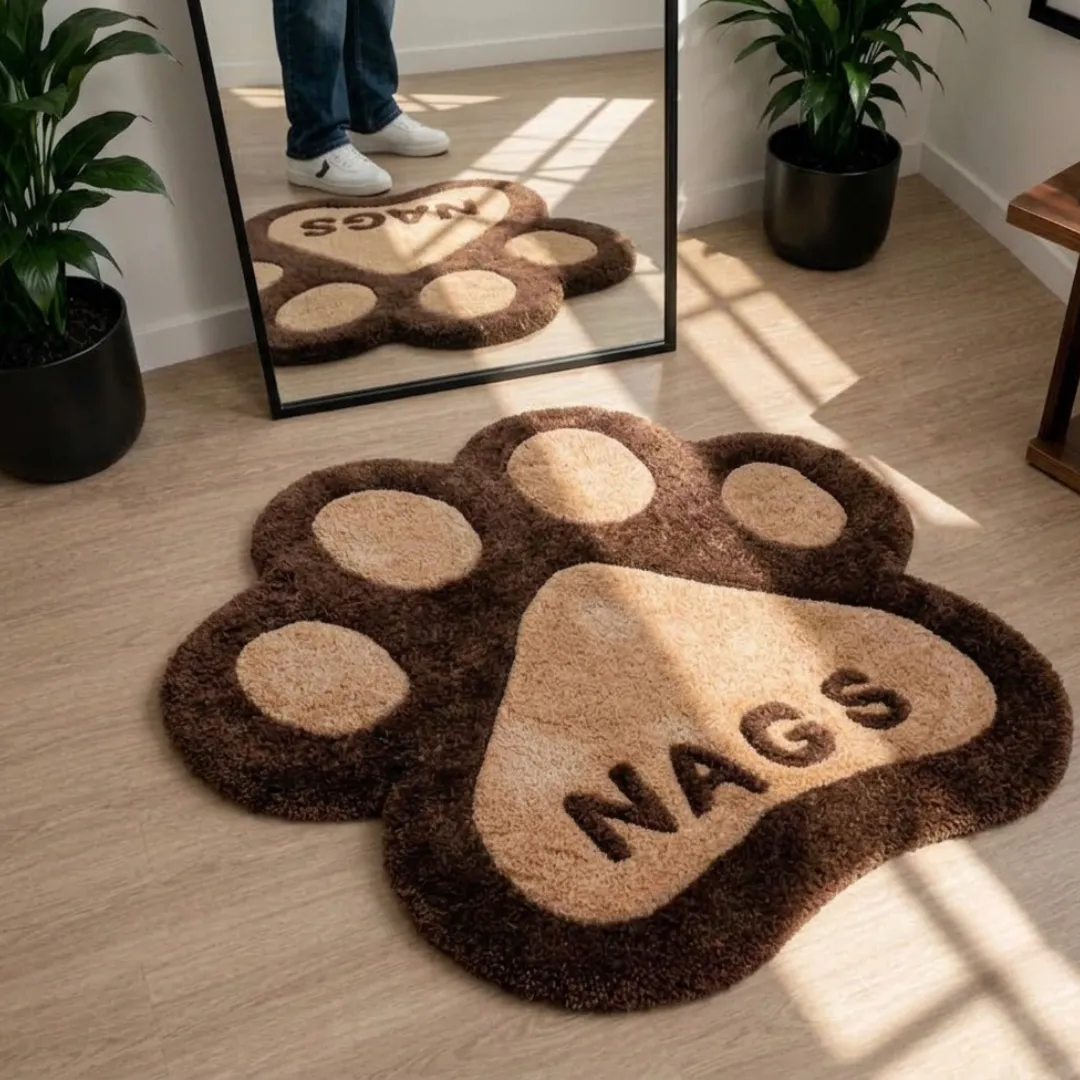 cocoa paw rug room layout view Cocoa Paw handmade tufted novelty area rug shaped like an animal paw in brown and beige with the word "NAGS" printed on the main pad, displayed on a wooden floor reflecting in a mirror.