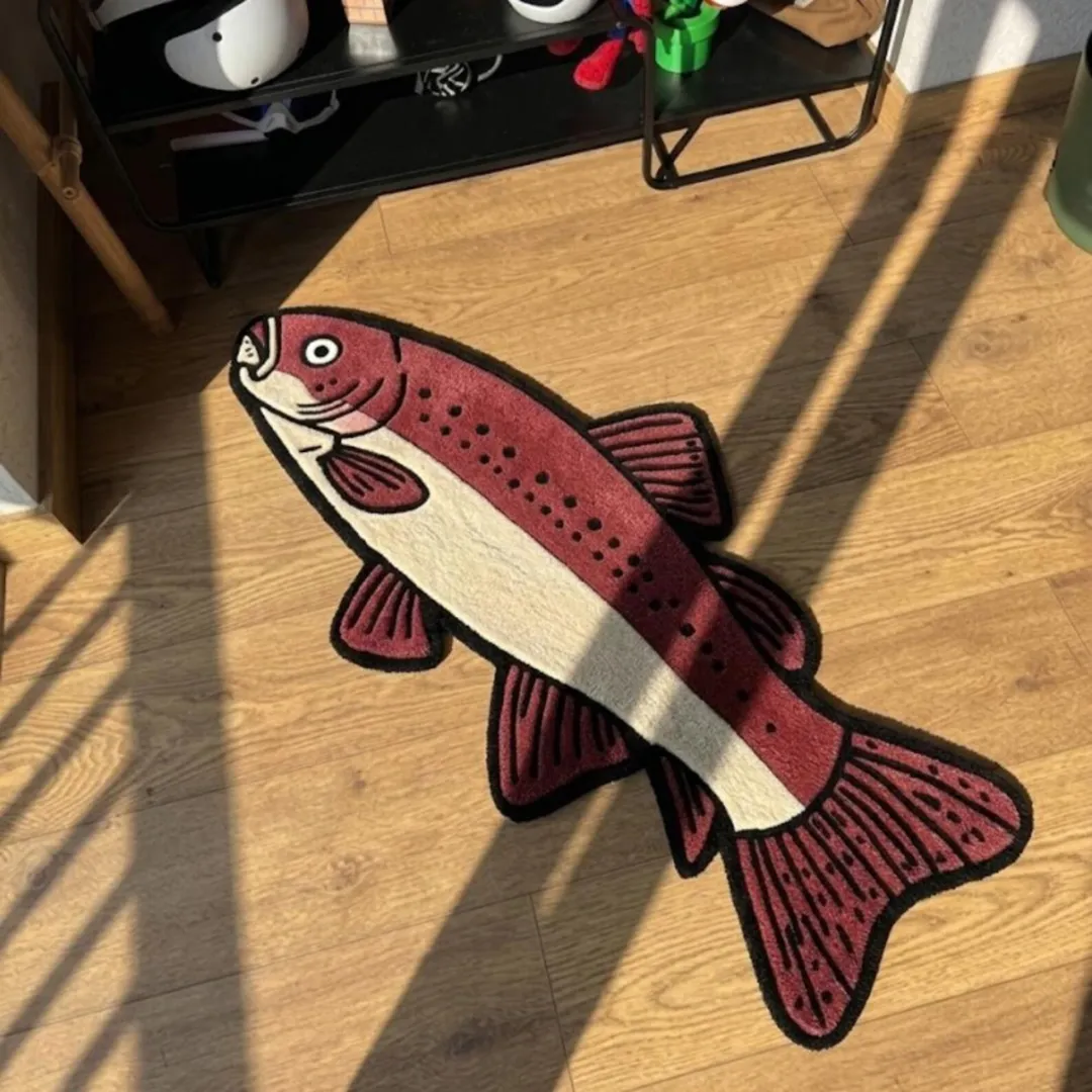 Crimson Trout handmade tufted novelty area rug shaped like a stylized fish in deep crimson and cream tones, displayed flat on a floor with shadow stripes.
