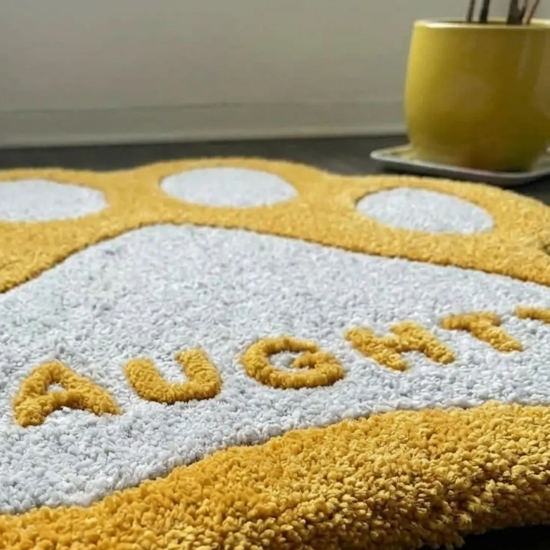 honey paw rug close up texture view Close-up macro texture shot of the high-density tufted wool pile, carved contours, and textured lettering on the Honey Paw designer rug.