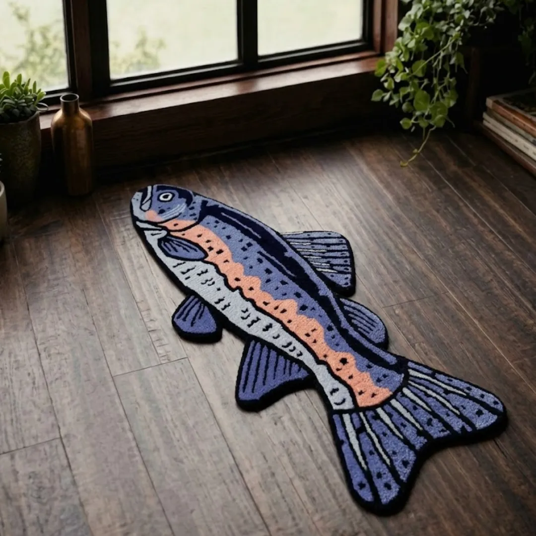 indigo trout rug alternative overhead view Indigo Trout handmade tufted novelty area rug shaped like a stylized fish in shades of blue, purple, and peach, displayed flat on a dark wooden floor near a window.