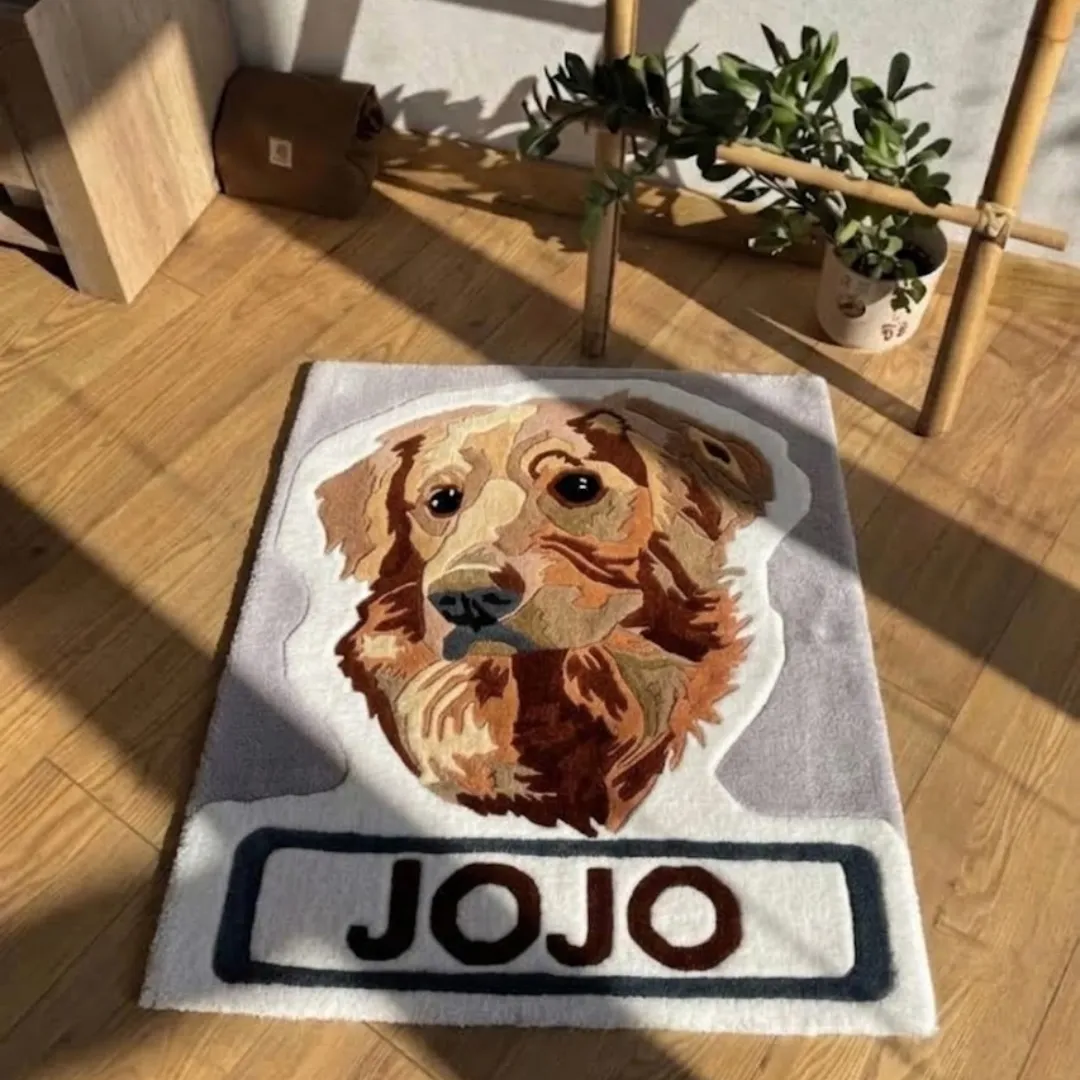 Jojo Golden handmade tufted rectangular area rug featuring a golden retriever portrait and the name "JOJO", displayed flat on a wooden floor in a sunny room.