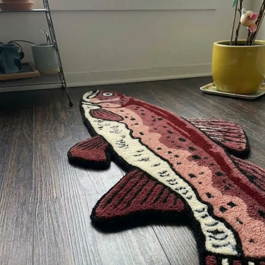 ruby trout rug close up texture view Low-angle view of the Ruby Trout tufted novelty rug showcasing its custom fish silhouette, plush wool pile, and rich color graduation on a hardwood floor.