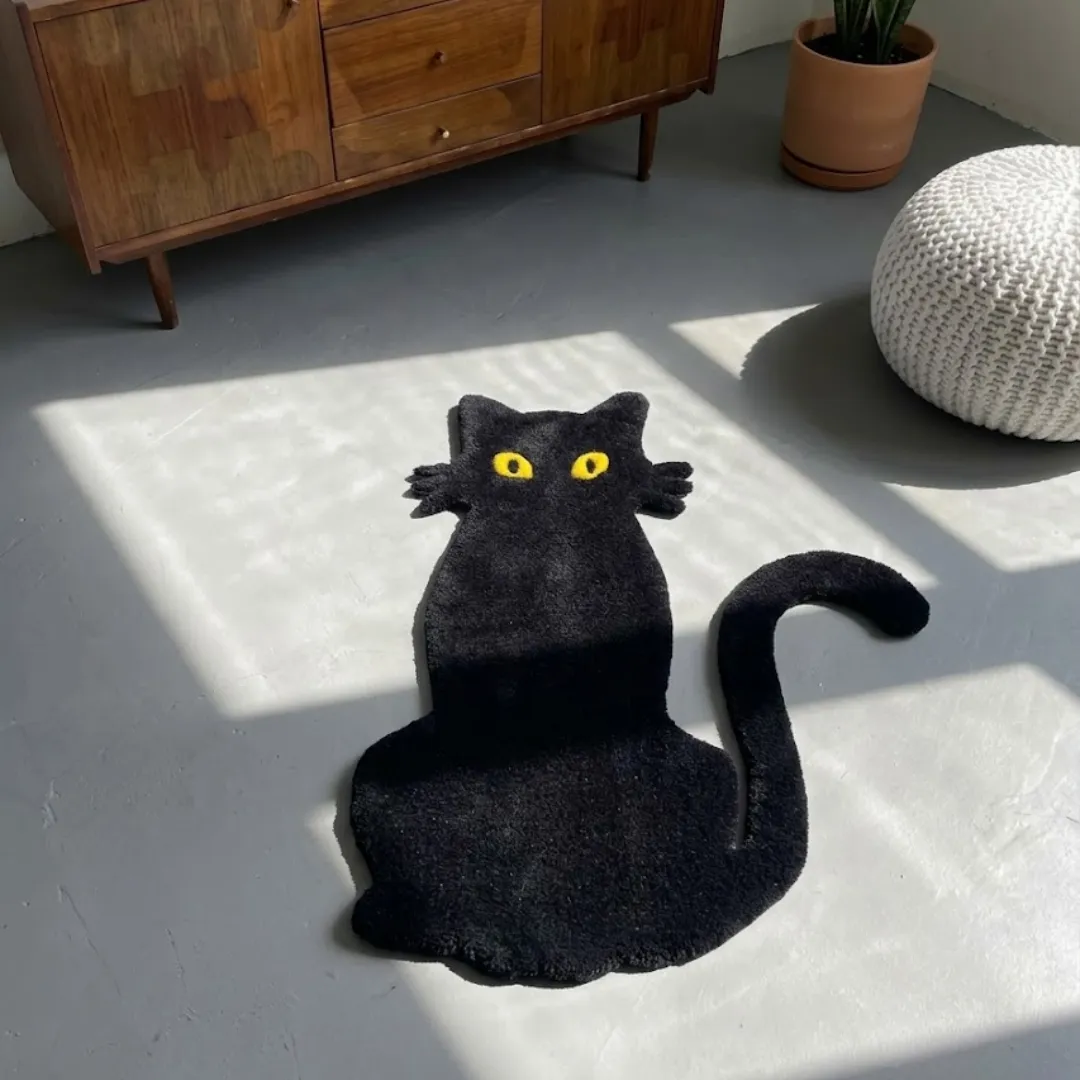 shadow meow rug overhead floor view Shadow Meow handmade tufted novelty area rug shaped like a black cat with striking yellow eyes, displayed flat on a modern gray floor.